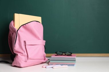 Boş yeşil karatahta, farklı kırtasiye, sırt çantası ve gözlük, metin için boşluk