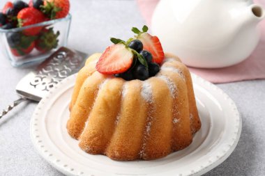 Açık gri masada pudra şekeri ve böğürtlenli Lezzetli kek, yakın plan.