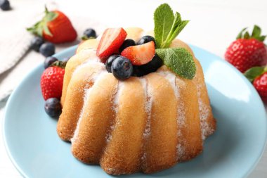 Beyaz masada pudra şekeri ve böğürtlenli leziz kek, yakın plan.