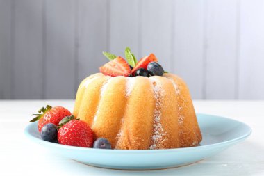 Beyaz ahşap masada pudra şekerli ve dutlu Lezzetli kek, yakın plan.