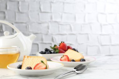 Lezzetli kek parçaları, böğürtlenli ve beyaz mermer masada çay, yakın plan.