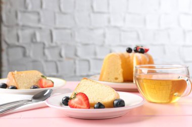 Böğürtlenli kek ve pembe ahşap masada çay, yakın plan.