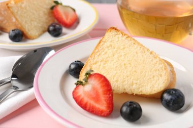 Lezzetli meyveli kek ve pembe masada çay, yakın plan.