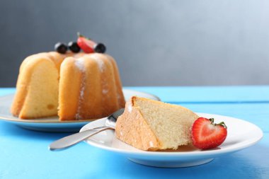 Açık mavi ahşap masada pudra şekerli ve dutlu Lezzetli kek, yakın plan.