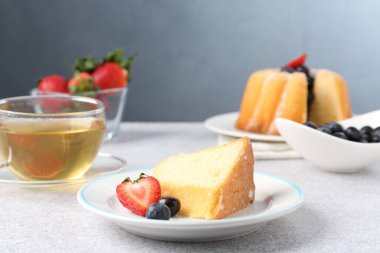 Açık gri masada böğürtlenli kek ve çay, yakın plan.