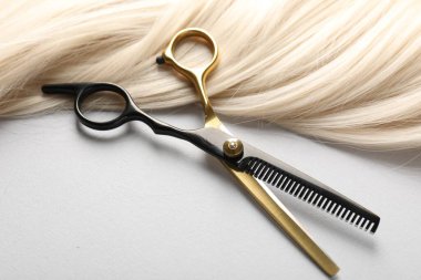 Sarı saç tokası ve makas açık gri arka planda, yakın plan.