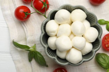 Lezzetli mozzarella peyniri topları, domates ve fesleğen beyaz ahşap masa, düz yatıyordu.