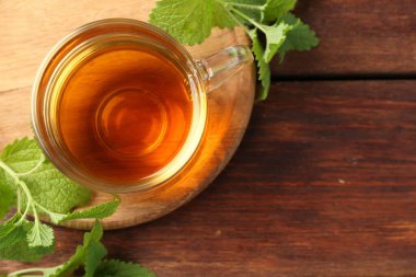 Cam bardakta Aromatik limon merhemi çayı ve ahşap masada taze yapraklar, üst manzara. Metin için boşluk