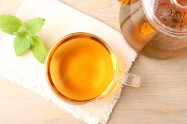 Cam bardakta Aromatik limon merhemi çayı, çaydanlık ve taze yapraklar ahşap masada, düz yerde.