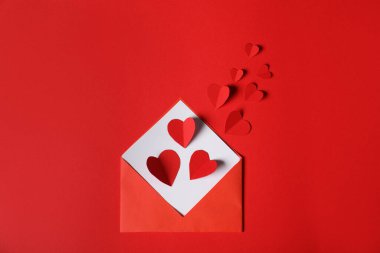 Kırmızı arka planda kağıttan kalpler uçuşuyordu.