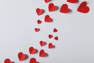 Açık gri arkaplanda bir sürü kağıt kalp var.