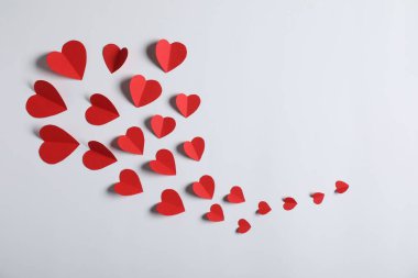 Açık gri arkaplanda bir sürü kağıt kalp var.