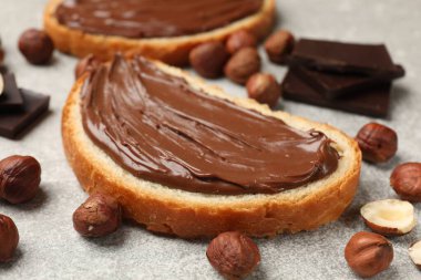 Çikolatalı fındıklı tostlar ve fındıklar gri masada, yakın plan.