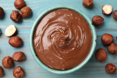 Lezzetli çikolatalı fındık ezmesi ve fındıklar mavi ahşap masada, düz yatıyordu.