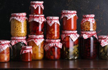 Ahşap masada farklı turşu ürünleri olan bir sürü kavanoz.