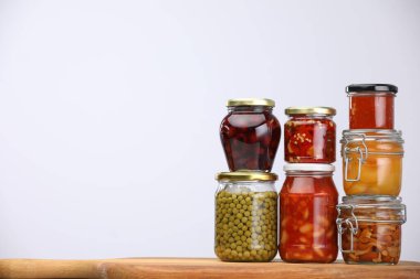 Açık gri arkaplan ile ahşap tahta üzerinde farklı turşu ürünleri olan birçok kavanoz, metin için alan