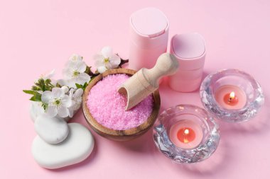 Kozmetik ürünleri, çakıl taşları ve pembe arka planda güzel çiçeklerle kaplıca kompozisyonu.