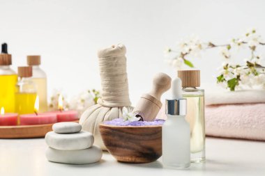 Spa ürünleri, güzel çiçekler ve beyaz masada yanan mumlar, yakın plan.