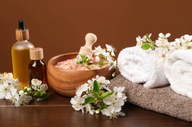 Kozmetik ürünleriyle kaplıca kompozisyonu ve ahşap masa üzerinde güzel çiçekler, yakın plan.