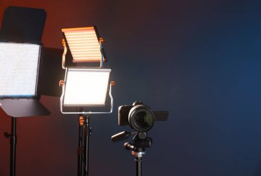 Profesyonel ışıklandırma ekipmanı ve renkli arka planda kamera. Metin için boşluk