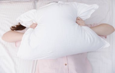 Kadın evinde yastıkla kendini örtüyor, manzaranın üstünde. Uykusuzluk sorunu