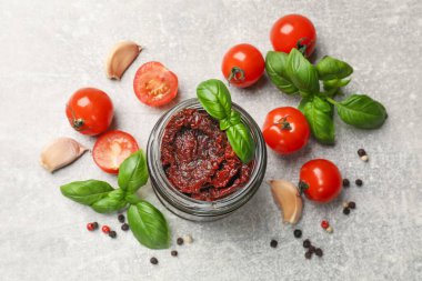 Lezzetli güneşte kurutulmuş domatesler, taze sebzeler, fesleğen ve sarımsak açık gri masada, düz yatıyordu.