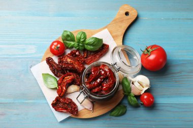 Lezzetli güneş, cam kavanozda kurutulmuş domatesler, taze sebzeler ve baharatlar açık mavi ahşap masa, düz uzanmış