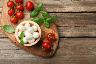Tabakta mozzarella peyniri topları, fesleğen, biber ve domatesler ahşap masada, üst manzara. Metin için boşluk