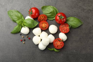 Mozzarella peyniri, domatesler, fesleğen ve biberler gri masada, düz yatıyordu.