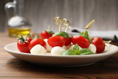 Ahşap masada mozarella, domates ve fesleğen ile aperatifler, yakın plan.