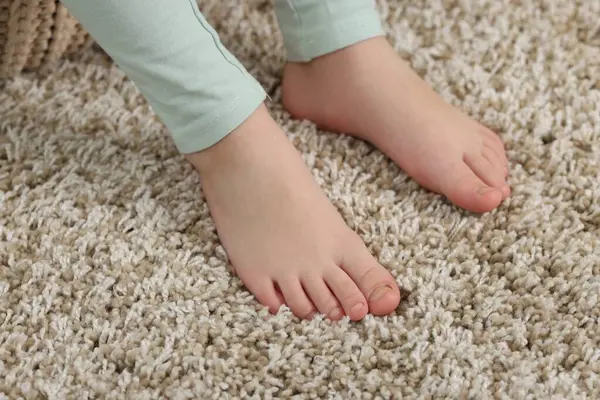 Evdeki yumuşak halıdaki kız, yakın plan.