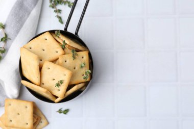 Lezzetli tuzlu krakerler ve kekik beyaz fayanslı masada, düz yerde.
