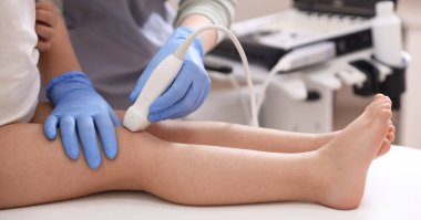 Sonograf, klinikte küçük kızın dizinin ultrason muayenesini yapıyor.