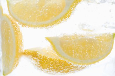 Beyaz arka planda limon dilimleri ile soda tazeleniyor, yakın plan.