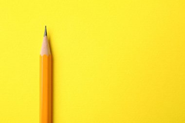 Sarı arka planda keskin bir grafit kalem, üst manzara. Metin için boşluk