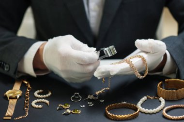Masadaki lüks mücevherleri değerlendiren eksper, yakın plan.