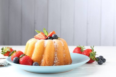 Beyaz ahşap masada pudra şekerli ve dutlu Lezzetli kek, yakın plan.