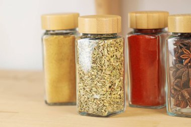 Kapalı alanda, ahşap masadaki kavanozlardaki farklı aromatik baharatlar.
