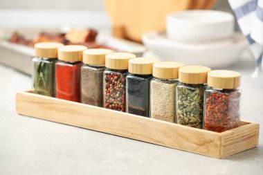 Işık masasındaki kavanozlarda farklı aromatik baharatlar, yakın plan.