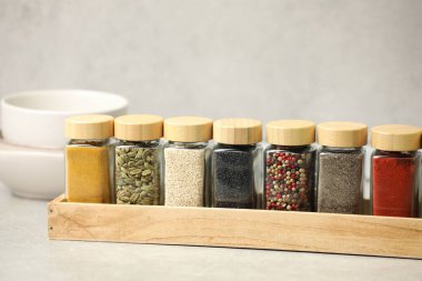 Işık masasındaki kavanozlarda farklı aromatik baharatlar, yakın plan.