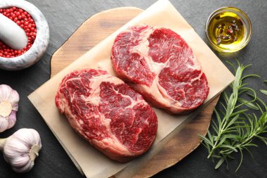 Çiğ et parçaları ve baharatlar siyah masanın üzerinde, düz yatıyordu.