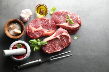 Çiğ et, baharat ve çatal parçaları gri masada, düz yerde. Metin için boşluk