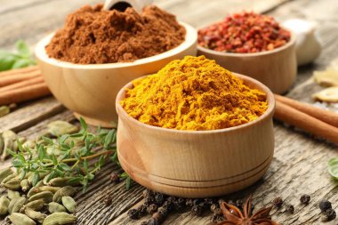 Ahşap masada farklı aromatik baharatlar, yakın plan.