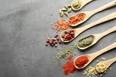 Gri masadaki kaşıklarda bir sürü farklı baharat var. Metin için boşluk