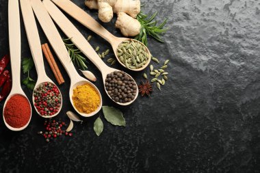 Siyah masadaki kaşıklarda bir sürü farklı baharat var. Metin için boşluk