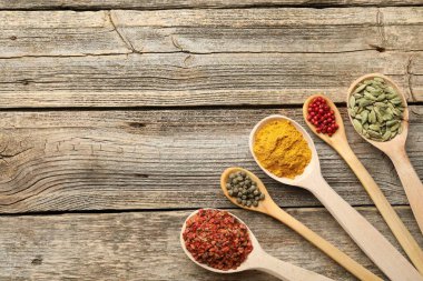 Tahta masadaki kaşıklardaki farklı aromatik baharatlar. Metin için boşluk