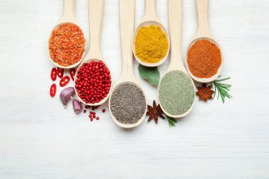 Beyaz ahşap masadaki kaşıklardaki farklı aromatik baharatlar.