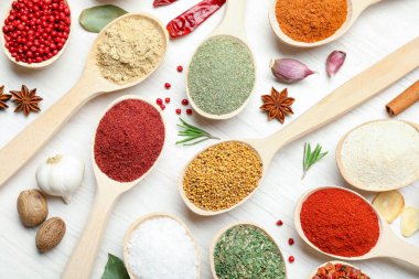 Beyaz ahşap masadaki kaşıklardaki farklı aromatik baharatlar.