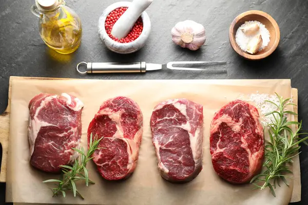 Çiğ et, baharat ve çatal parçaları siyah masaya, düz yatıyordu.