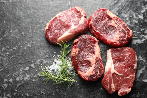 Koyu masa üzerinde çiğ et ve baharat parçaları, düz. Metin için boşluk